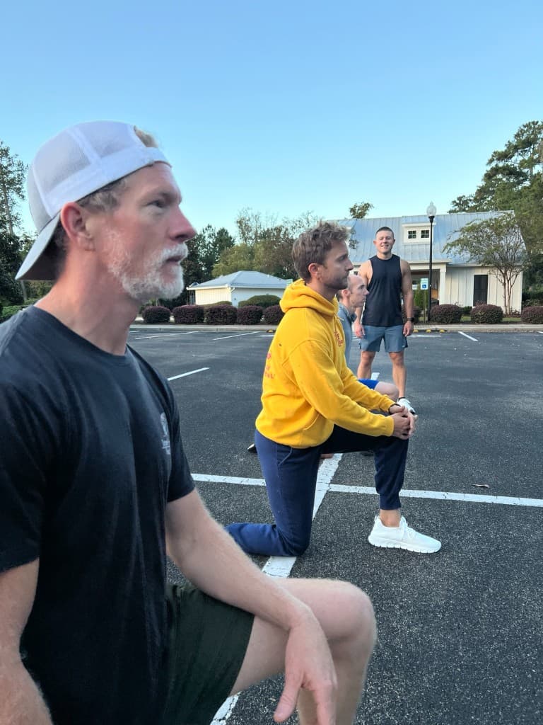 Men of different ages in a kneeling lunge line on the asphalt, focused and working together